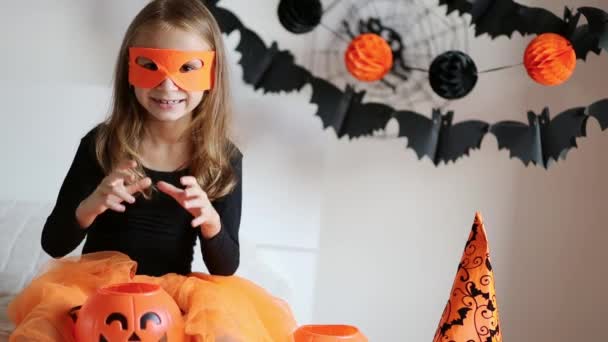 Niña en traje de bruja con cubo de caramelo de calabaza de Halloween en casa, evoca y hacer magia. Fiesta de Halloween. Decoración festiva para el hogar — Vídeos de Stock