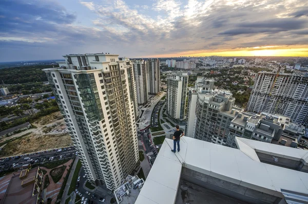 Un hombre en la cima de un rascacielos mirando a la ciudad — Foto de Stock