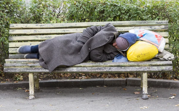 Homem sem-teto dormindo em um banco — Fotografia de Stock