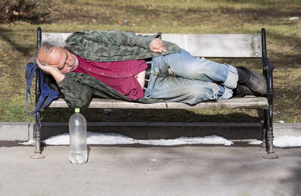 Senzatetto che dorme su una panchina — Foto Stock