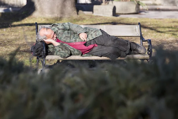 Бездомный на скамейке — стоковое фото