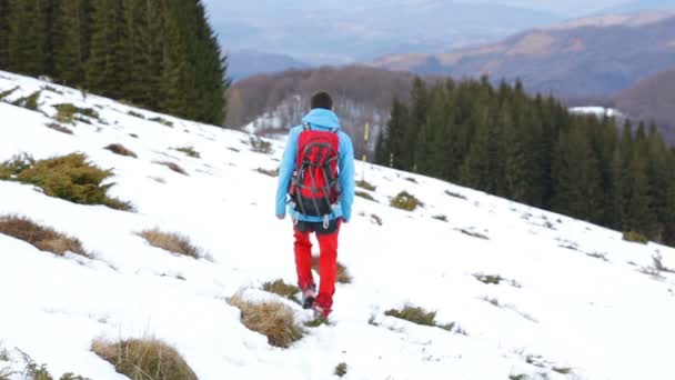 Um homem caminhando na montanha nevada — Vídeo de Stock
