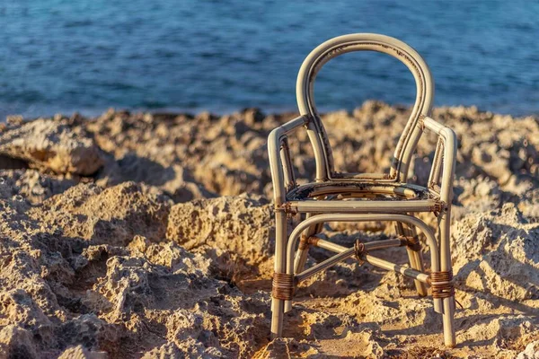 Dallardan yapılmış hasır sandalye bulanık mavi deniz arka planına yakın.