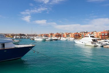 Hurghada marinasından demirlemiş yatlara, teknelere, gemilere ve şehrin dükkan, kafe ve arka planda yürümek için yaya bölgesine kadar panoramik manzara.