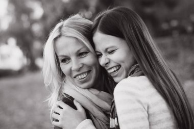 Doğada anne ve kızın monokrom portresini kapatıyorlar, birbirlerine omuzlarından sarılıyorlar ve gülüyorlar, birlikte mutlu anlar geçiriyorlar.