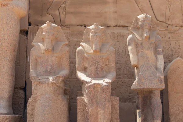 Luxor 'daki Amun Ra tapınağının duvarlarında antik Mısır firavunlarının granit heykelleri, arka planda hiyerogliflerle dolu bir duvar.