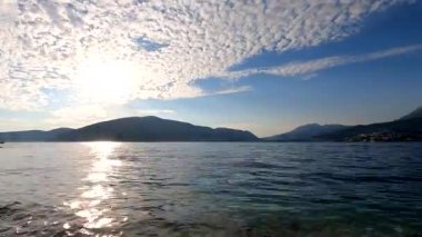 Kotor Körfezi 'nde günbatımının panoraması hızlandırılmış modda. Hareket eden bulutlar, güneş ışınları, sudaki dalgalar, botlar plana dinamik katıyor. Herceg Novi 'nin Forte Rose seti manzarası