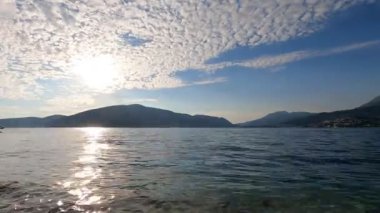 Kotor Körfezi 'nde günbatımının panoraması hızlandırılmış modda. Hareket eden bulutlar, güneş ışınları, sudaki dalgalar, botlar plana dinamik katıyor. Herceg Novi 'nin Forte Rose seti manzarası