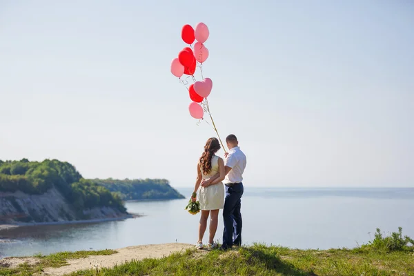 Happy wedding couple with red balloons — Stock Photo, Image