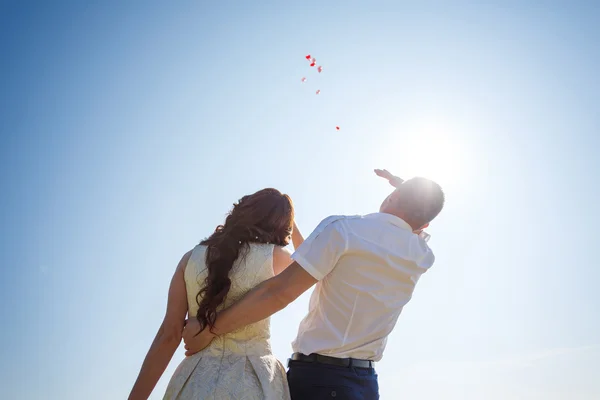Glückliches Hochzeitspaar mit roten Luftballons — Stockfoto