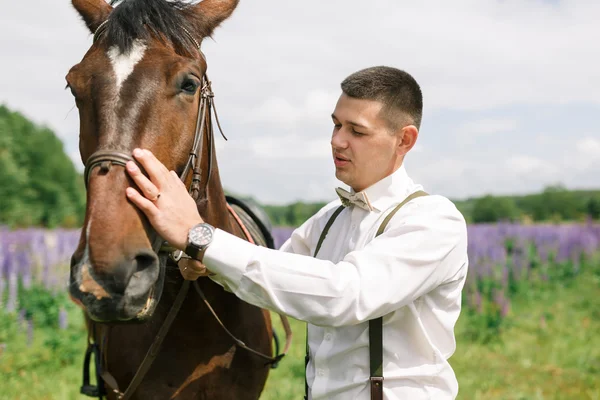 Pan młody z koniem na polu — Zdjęcie stockowe
