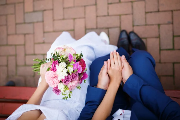 Gelin ve damat bankta parlak giysiler içinde.