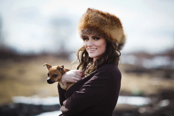 Portrait d'une belle fille souriante dans un chapeau de fourrure avec petit chien — Photo