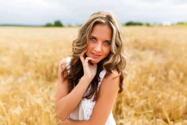Ung vacker flicka i ett vete fält — Stockfoto