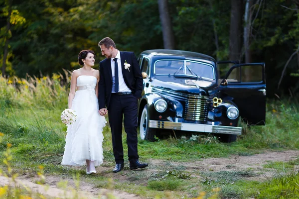 Um casal de casamento com carro velho — Fotografia de Stock