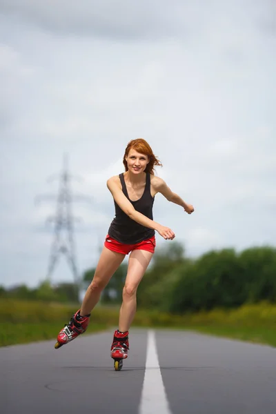 Muchacha atractiva patinando en el camino — Foto de Stock