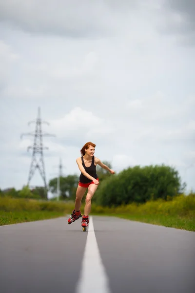 A vonzó lány görkorcsolya az úton — Stock Fotó