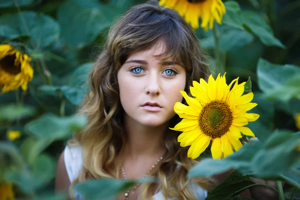 Attraktiv ung flicka i fältet av solrosor — Stockfoto