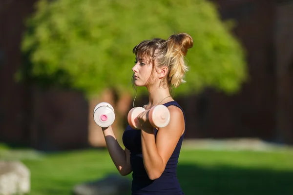 Молодая девушка упражняется с гантелями — стоковое фото