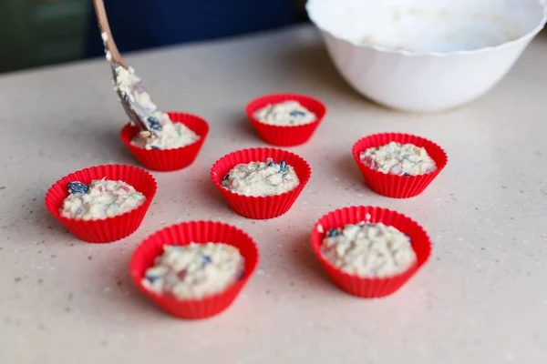 Young woman puts dough into shapes for muffins — Stock Photo, Image