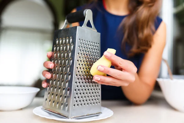 Young woman grating ginger — Stockfoto