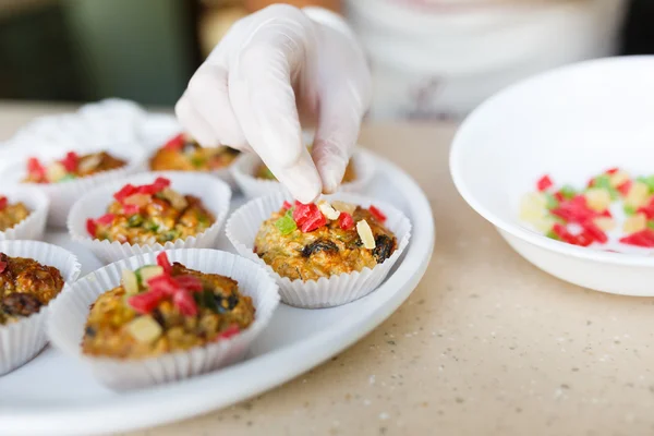 Young woman puts candied fruits on the cakes