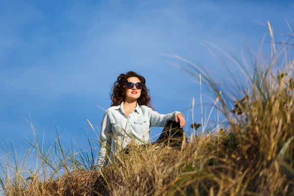 Young woman sitting in a dune — Stock Photo, Image