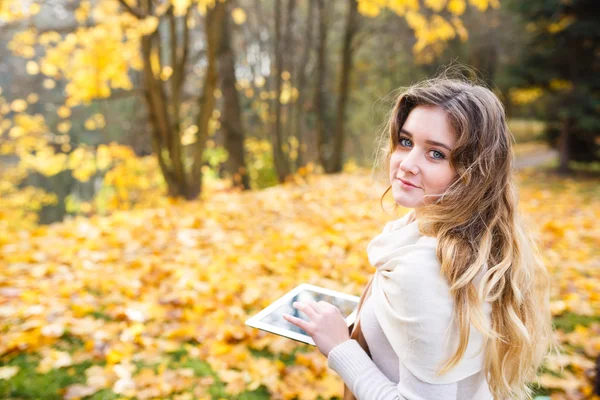 Mädchen mit Tablette im Herbst — Stockfoto