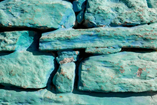 Rough old stone wall, part of stony masonry painting of blue color. Texture background