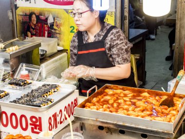 Seul, Güney Kore - 21 Haziran 2017: Seul 'deki Gwangjang pazarında müşterilere hizmet veren kadın satıcı. Kimbap, teokbokki, bibibimbap, kimchi alabileceğiniz en popüler sokak yemeklerinden biri..