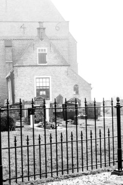 Den Hoorn, Hollanda - 25 Şubat 2010: Sonbahar sisli sabahı, Hollanda 'nın Texel Adası' ndaki Den Hoorn kilisesinin önündeki mezarlık.