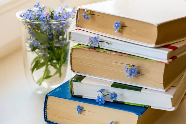 Montón Libros Con Pequeñas Flores Azules Entre Páginas Mesa Blanca — Foto de Stock