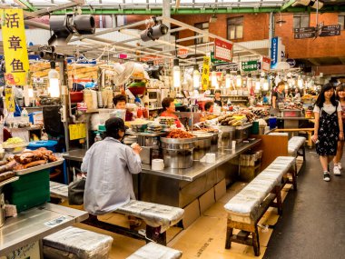 Seul, Güney Kore - 21 Haziran 2017: Seul 'deki Gwangjang Market' te lezzetli yiyecek ve içecekler yiyen insanlar.