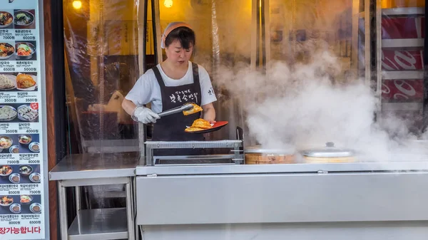 Seul, Coréia do Sul - 23 de junho de 2017: Vendor mulher fritando bolinhos no quiosque de fast food no centro de Seul — Fotografia de Stock