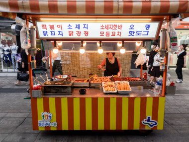 Suwon, Güney Kore - 15 Haziran 2017: Suwon 'daki ana caddede fast food büfesinde alıcıları bekleyen kadın satıcısı. Sokak yemekleri Kore 'de çok popülerdir..