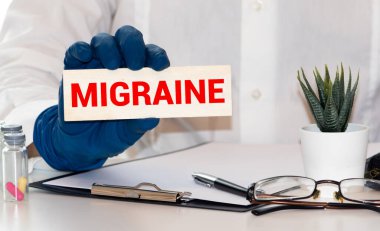 Tablet bilgisayarında migren kelimesi ahşap arka planda.