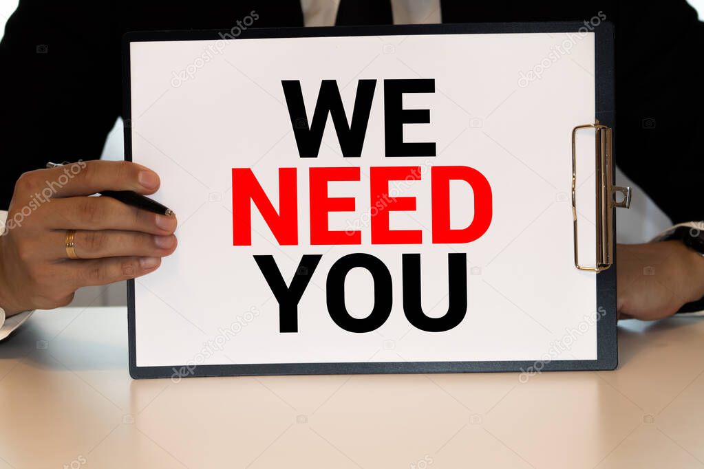 WE NEED YOU. message on the card shown by a man.