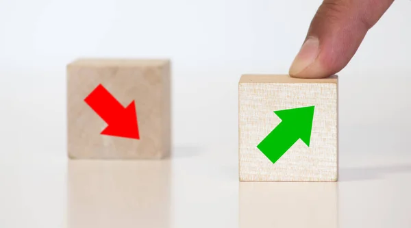 The hand separates two wooden blocki with red arrow down and green arrow up.