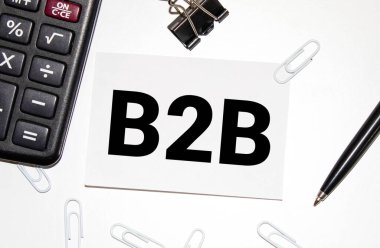İş ve finans kavramı. Masanın üzerinde bir saat, bir kalem ve üzerinde B2B yazan bir kart var. İŞE İŞE