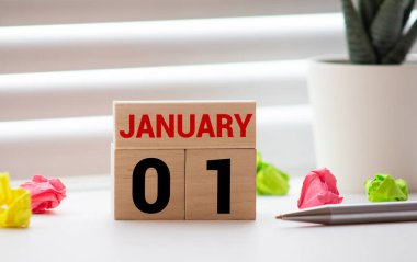 1 Ocak. Beyaz tahta blok takvimi 01 ve 1 Ocak tarihlerini fotokopi alanı ile ahşap zemin üzerinde gösteriyor. Yeni yıl günü.