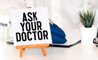 Çalar saat, steteskop, cep telefonu ve küçük siyah tahta levha. Tahta arka planda doktorunuza sorun..