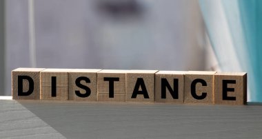 Beyaz arkaplanda tahta zemine küp şeklinde yazılmış DISTANCE kelimesi, metin veya diğer resim veya tasarım eklemek için harf blokları farklı sözcüklere ayrılır
