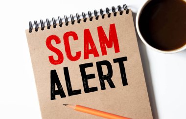 Ahşap arka planda Scam Alarmı ile not.