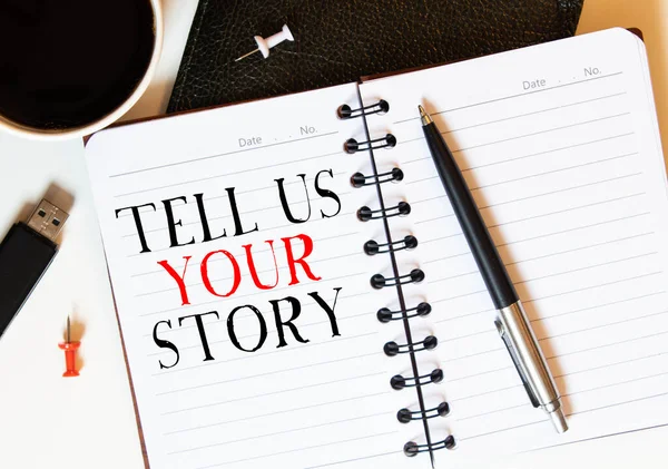 TELL US YOUR STORY text on white paper