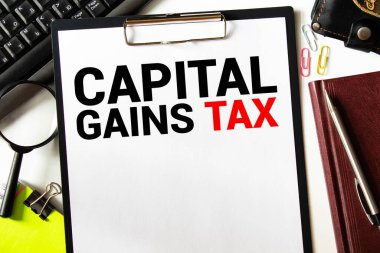 Üzerinde CAPITAL GAINS Vergi yazan bir kart tutan işadamına yakın plan, yumuşak odaklı iş konsepti resmi ve klasik ton