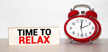 Etiketteki TIME kelimeleri, ahşap bir masanın üzerindeki çalar saatin yanında..