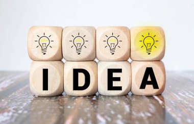 Yaratıcı fikir ve yenilik kavramı. İnsan sembolü ve ampul simgesiyle ahşap küp bloğunu ters çevir