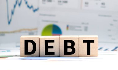 Küp tahta kelime borcunu ve para destesini masa tahtası beyaz arka planda engeller. Mali borç kavramını azaltır.