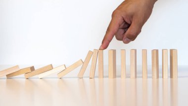 Domino etkisini durduran ve koruyan iş adamı eliyle risk konsepti.