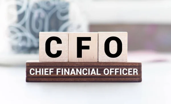 CFO Chief Financial Officer written on a wooden cube in front of a laptop.